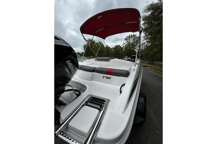 Slide: The Image of 2025 Tahoe T16 boat with red canopy and Mercury engine, parked outdoors. - 8