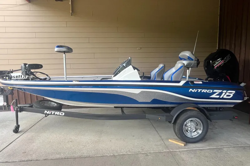 The Image of 2025 Nitro Z18 Pro boat on trailer, blue and gray design, parked indoors. - 0