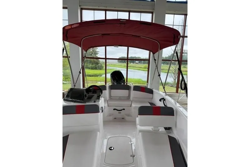 Slide: The Image of 2025 Tahoe T16 boat interior with red canopy, spacious seating, and scenic window view. - 4