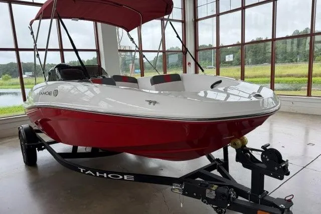 The Image of 2025 Tahoe T16 boat with red and white design on a trailer in a showroom. - 0