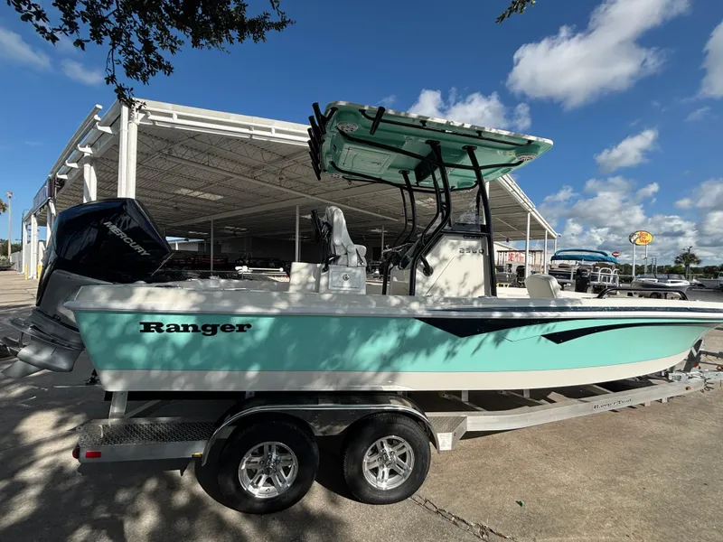 The Image of 2025 Ranger 2360 Bay boat on trailer, parked outdoors under blue sky. - 0