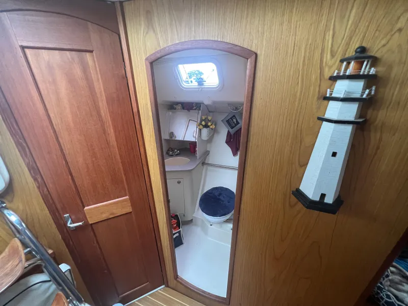 Slide: The Image of Interior of a 2000 Hunter 410 sailboat with wooden paneling and a compact bathroom. - 43