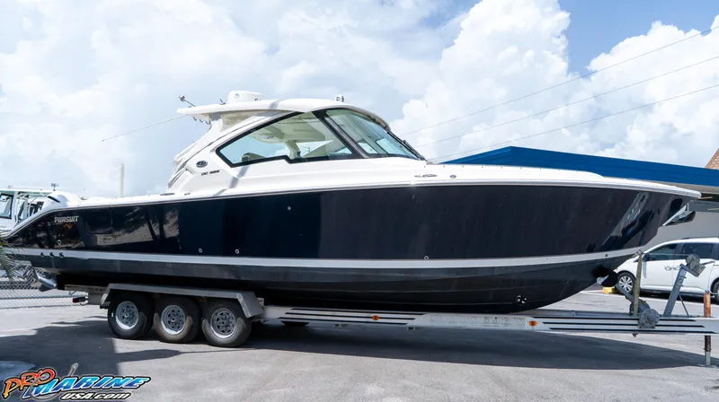 Slide: The Image of 2021 Pursuit DC 326 Dual Console boat on a trailer, parked outdoors. - 11