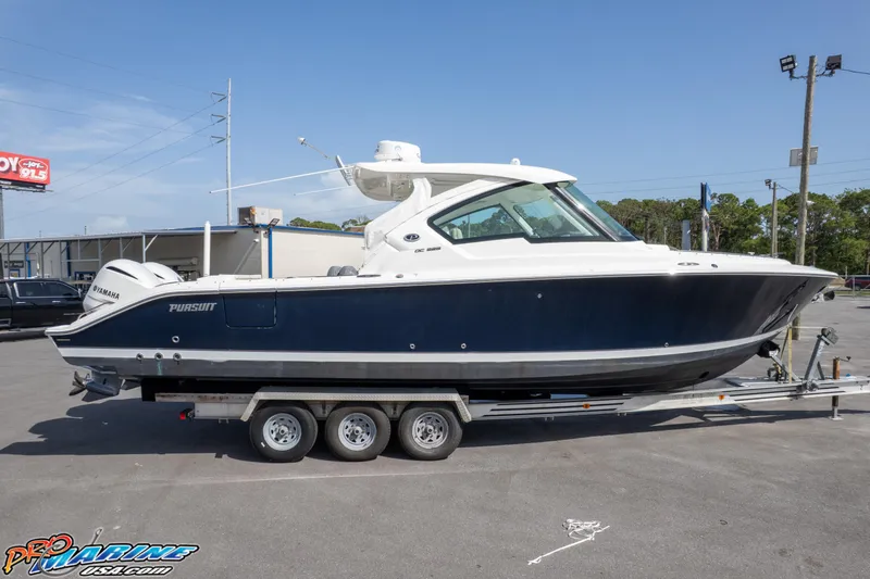 Slide: The Image of 2021 Pursuit DC 326 Dual Console boat on a trailer in a parking lot. - 24