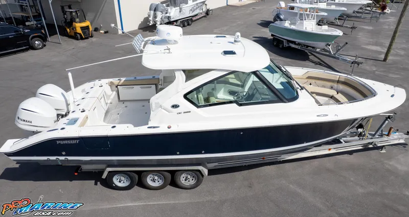 Slide: The Image of 2021 Pursuit DC 326 Dual Console boat on trailer, parked in a marina. - 25