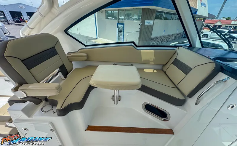 Slide: The Image of 2021 Pursuit DC 326 Dual Console interior with beige seating and compact table. - 37