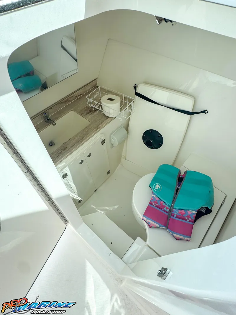 Slide: The Image of 2021 Pursuit DC 326 Dual Console boat interior with sink, toilet, and life jackets. - 48
