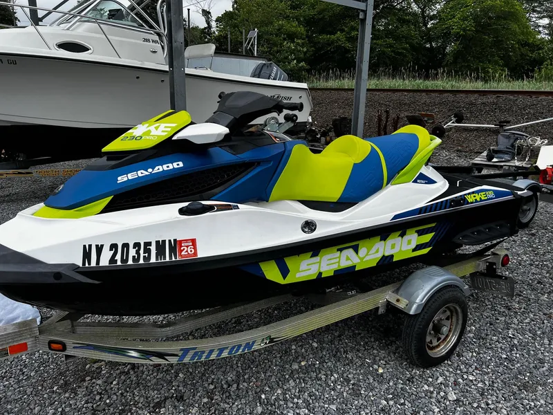 The Image of 2017 Sea-Doo Wake Pro 230 jet ski on trailer, vibrant blue and green design. - 0