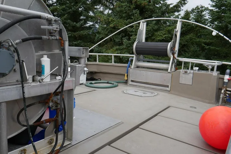 Slide: The Image of Custom Freestyle Marine 32 deck with equipment, hose, and red buoy, surrounded by trees. - 11