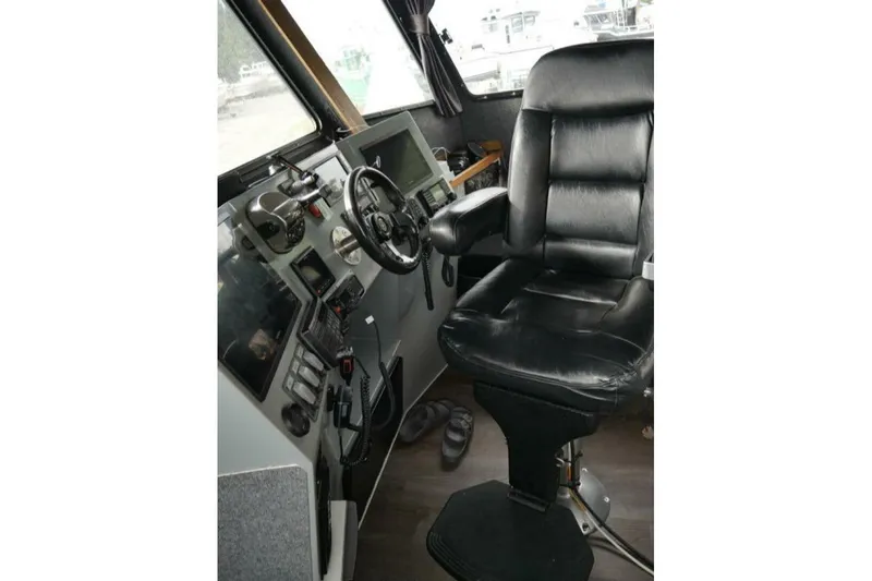 Slide: The Image of Interior of 2022 Custom Freestyle Marine 32 boat with black captain's chair and control panel. - 13