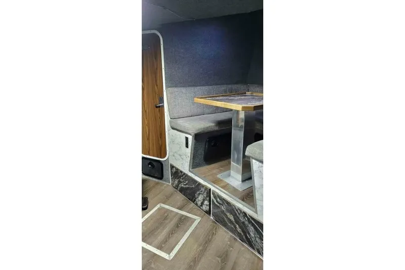Slide: The Image of Interior of 2022 Custom Freestyle Marine 32, featuring a cozy seating area with a wooden table. - 23