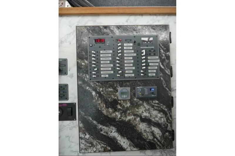 Slide: The Image of Electrical control panel on 2022 Custom Freestyle Marine 32 boat, featuring switches and digital displays. - 25