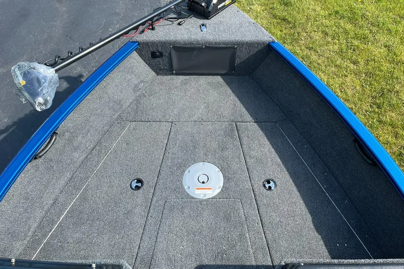 Slide: The Image of 2026 Lund 1675 Adventure Sport boat deck with gray carpet and blue trim. - 14