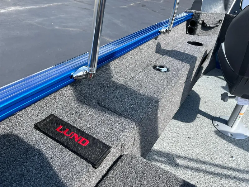 Slide: The Image of 2026 Lund 1675 Adventure Sport boat interior with gray carpet and blue trim. - 21