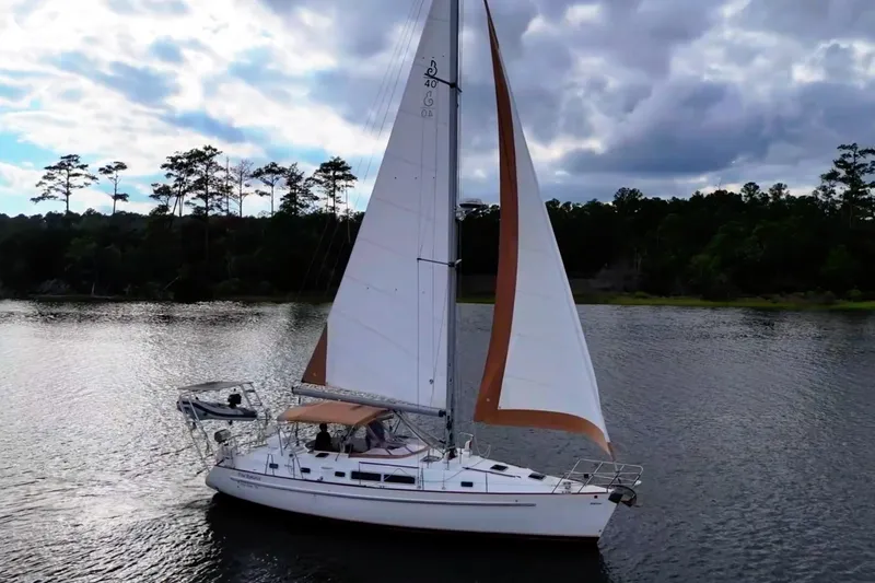 Slide: The Image of 1997 Beneteau Oceanis 40 CC sailboat on a serene lake under cloudy skies. - 9