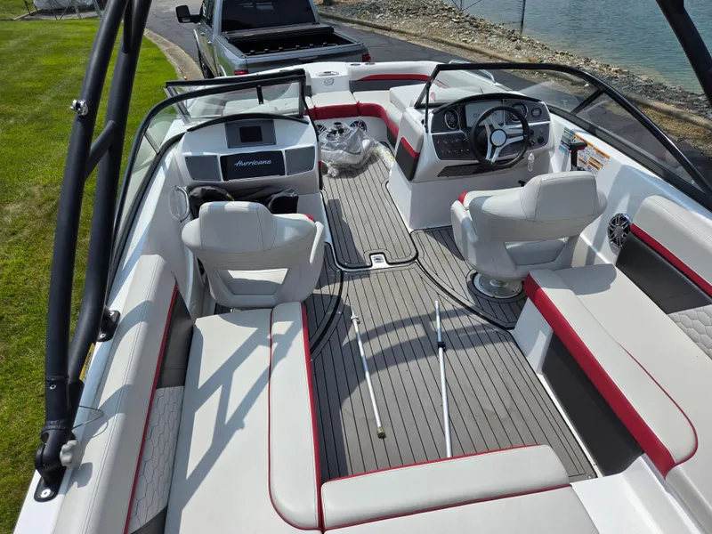 Slide: The Image of 2021 Hurricane SunDeck 217 OB boat interior with seating and steering wheel, near water. - 11