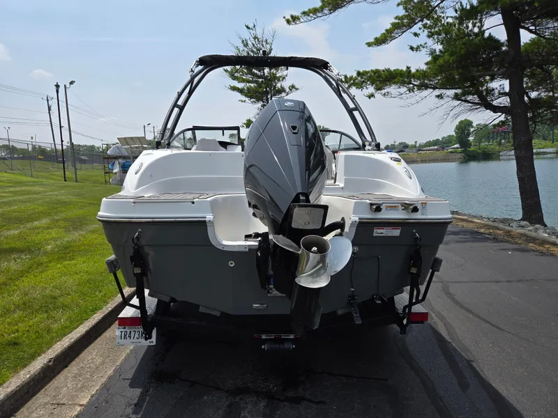 Slide: The Image of 2021 Hurricane SunDeck 217 OB boat parked near a lake, rear view. - 2