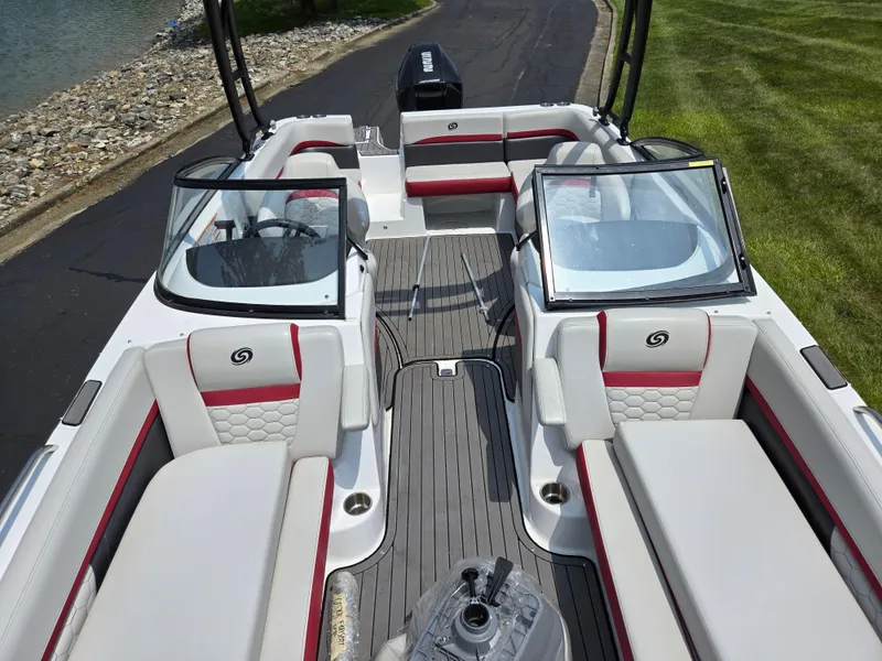 Slide: The Image of 2021 Hurricane SunDeck 217 OB boat interior with red and white seating, docked by a lake. - 21