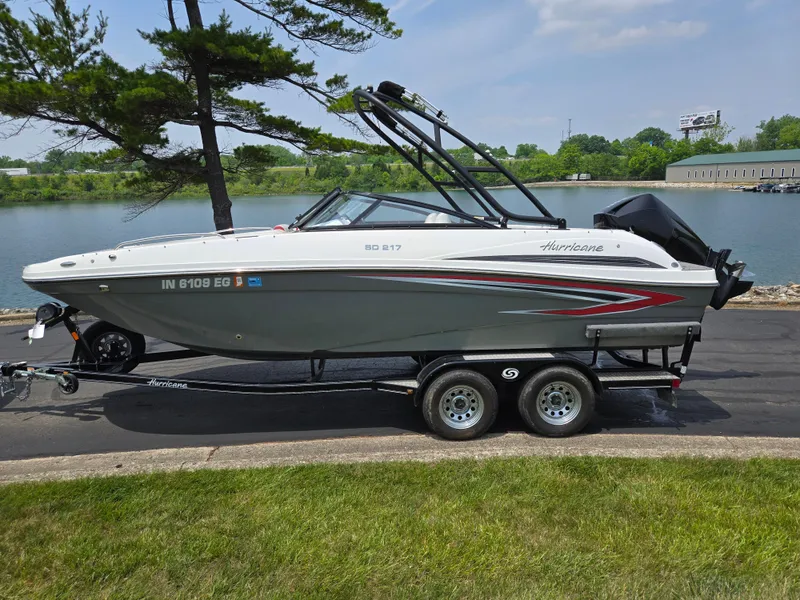 Slide: The Image of 2021 Hurricane SunDeck 217 OB boat on trailer by a scenic lake. - 9