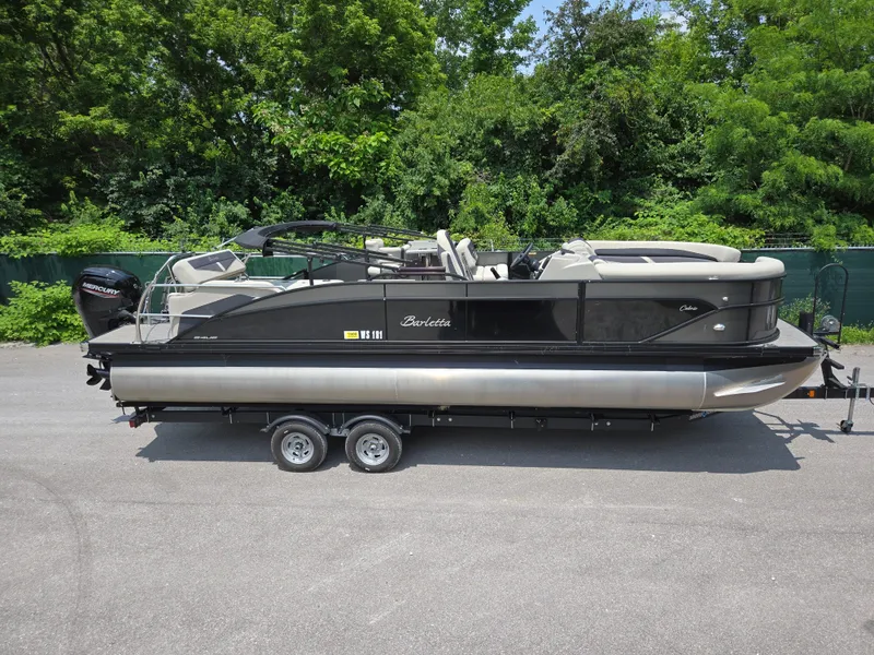 The Image of 2023 Barletta Cabrio 24UE pontoon boat on trailer, surrounded by greenery. - 0