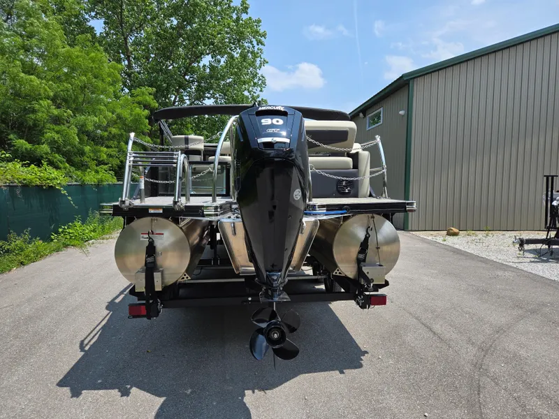 Slide: The Image of 2023 Barletta Cabrio 24UE pontoon boat with outboard motor, parked outdoors. - 2