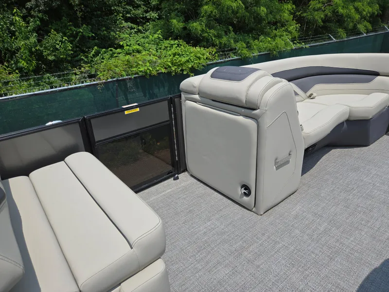 Slide: The Image of 2023 Barletta Cabrio 24UE pontoon boat interior with plush seating and lush greenery backdrop. - 27