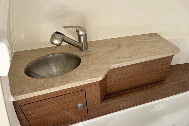 Slide: The Image of 2026 Boston Whaler 280 Vantage boat sink with modern faucet and wooden cabinetry. - 18