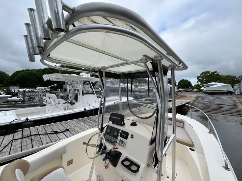 Slide: The Image of 2014 Scout 195 Sportfish boat with center console and T-top at a marina. - 12