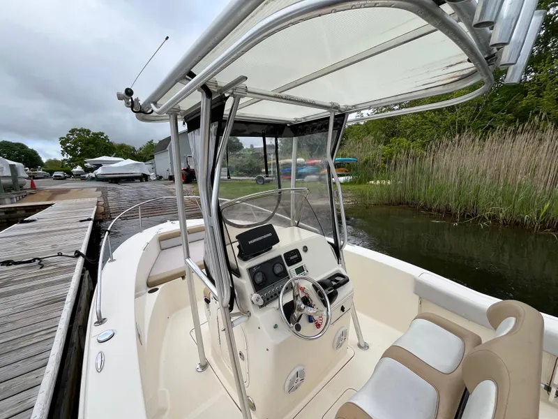 Slide: The Image of 2014 Scout 195 Sportfish boat docked, featuring a sleek console and comfortable seating. - 13