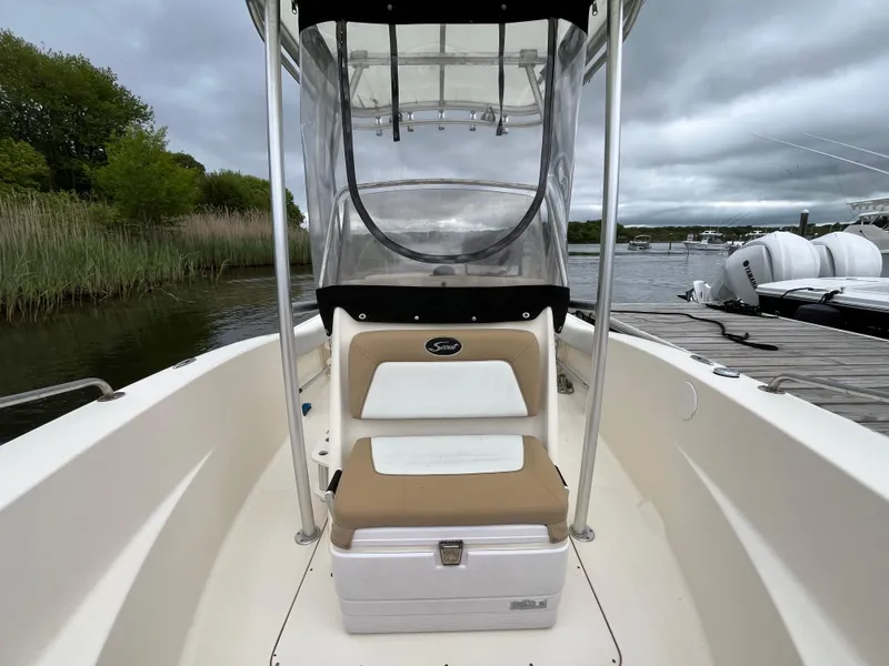 Slide: The Image of 2014 Scout 195 Sportfish boat with center console, docked by a lake under cloudy skies. - 16