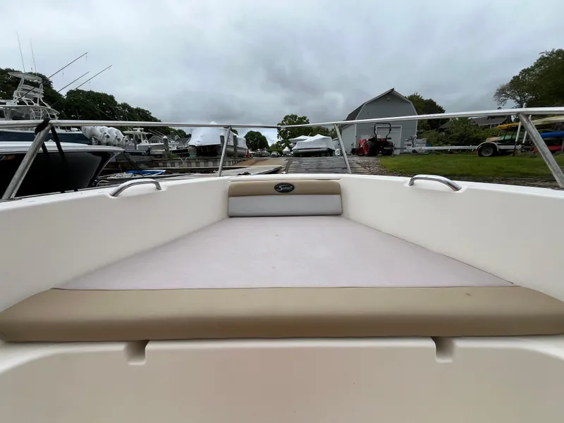 Slide: The Image of 2014 Scout 195 Sportfish boat interior with cushioned seating, docked at a marina. - 18