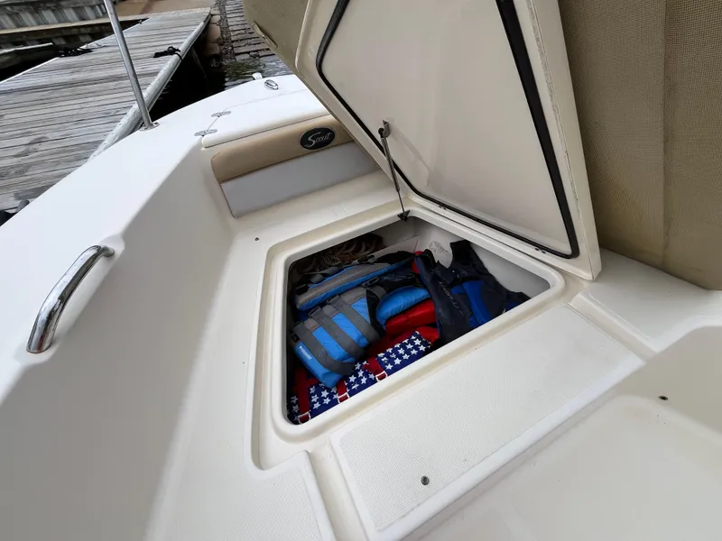 Slide: The Image of 2014 Scout 195 Sportfish boat storage compartment with life jackets and gear. - 19
