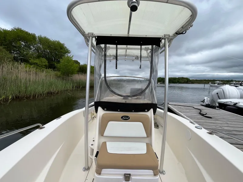 Slide: The Image of 2014 Scout 195 Sportfish boat with canopy, docked by a serene lake. - 21