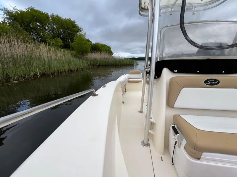 Slide: The Image of 2014 Scout 195 Sportfish boat navigating a narrow waterway with lush greenery. - 23