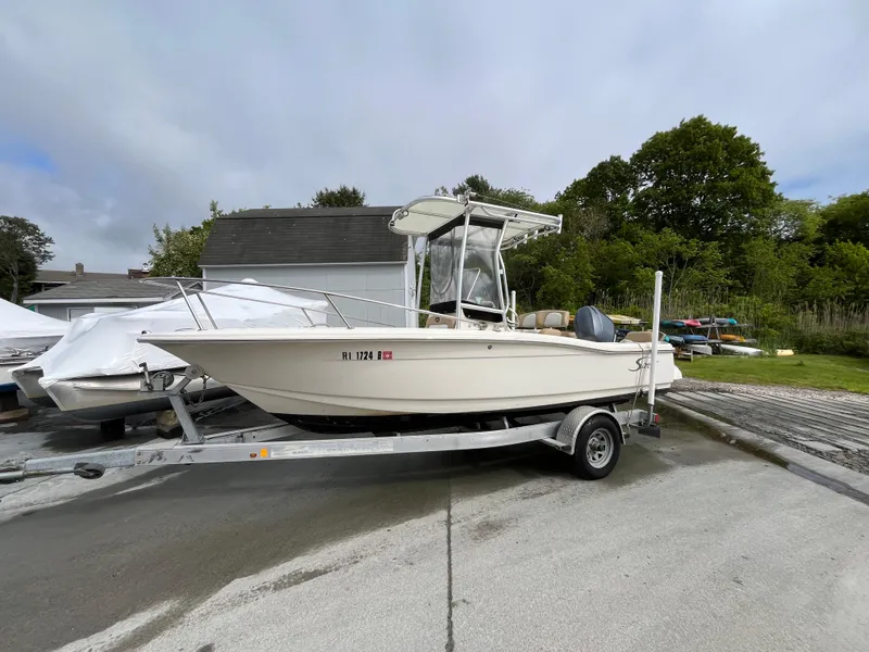Slide: The Image of 2014 Scout 195 Sportfish boat on trailer, parked outdoors near trees and buildings. - 4