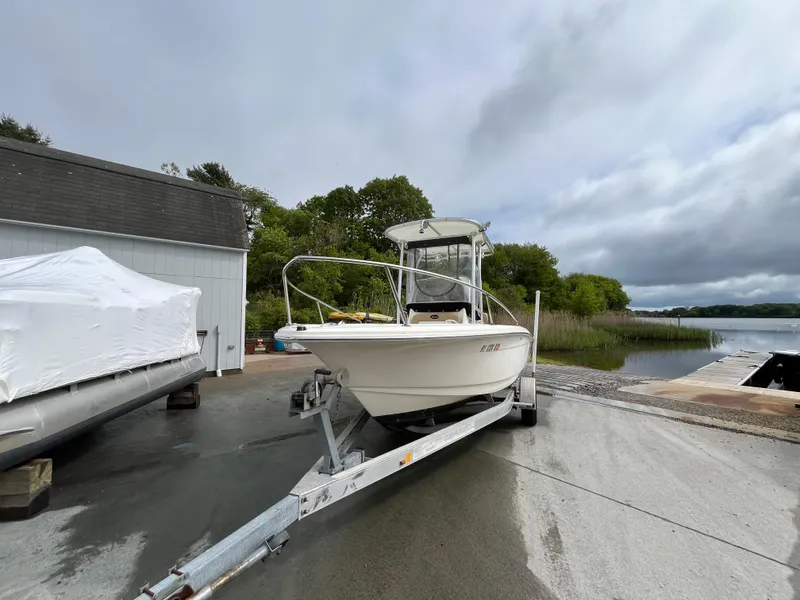 Slide: The Image of 2014 Scout 195 Sportfish boat on trailer near waterfront, overcast sky. - 5