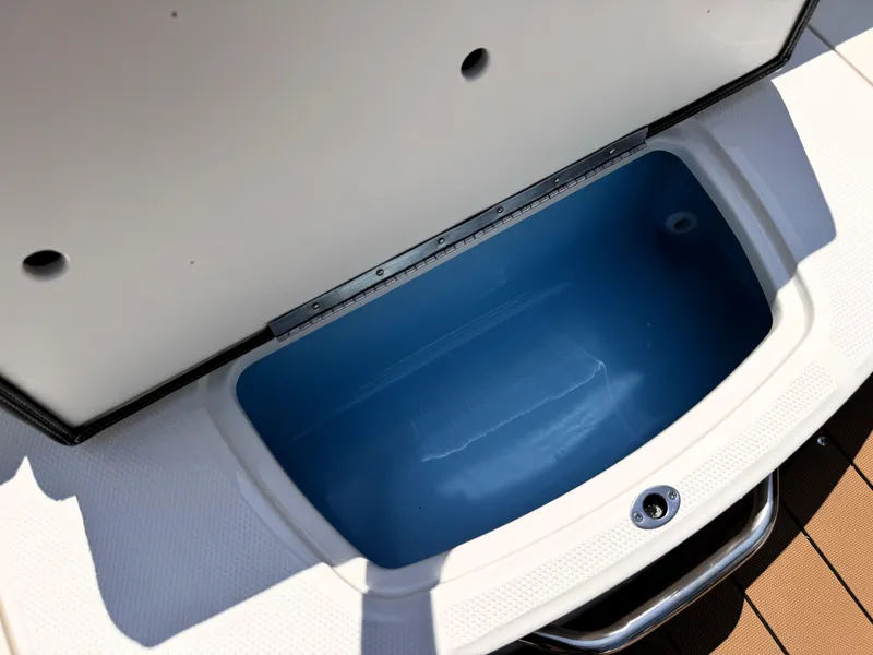 Slide: The Image of Open storage compartment on 2025 Chaparral 21 SSi OB boat, featuring a blue interior. - 17