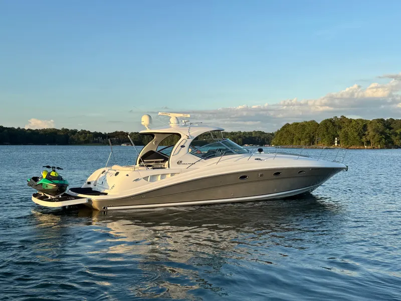 Slide: The Image of 2005 Sea Ray 420 Sundancer yacht on calm water with jet ski, under clear sky. - 18