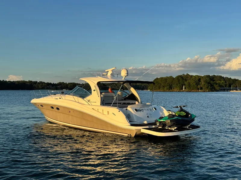 Slide: The Image of 2005 Sea Ray 420 Sundancer yacht on calm water with jet ski, under clear sky. - 9