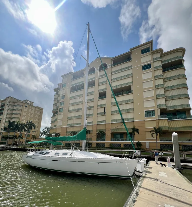 Slide: The Image of 1995 Beneteau First 42s7 sailboat docked near waterfront apartments under a sunny sky. - 31