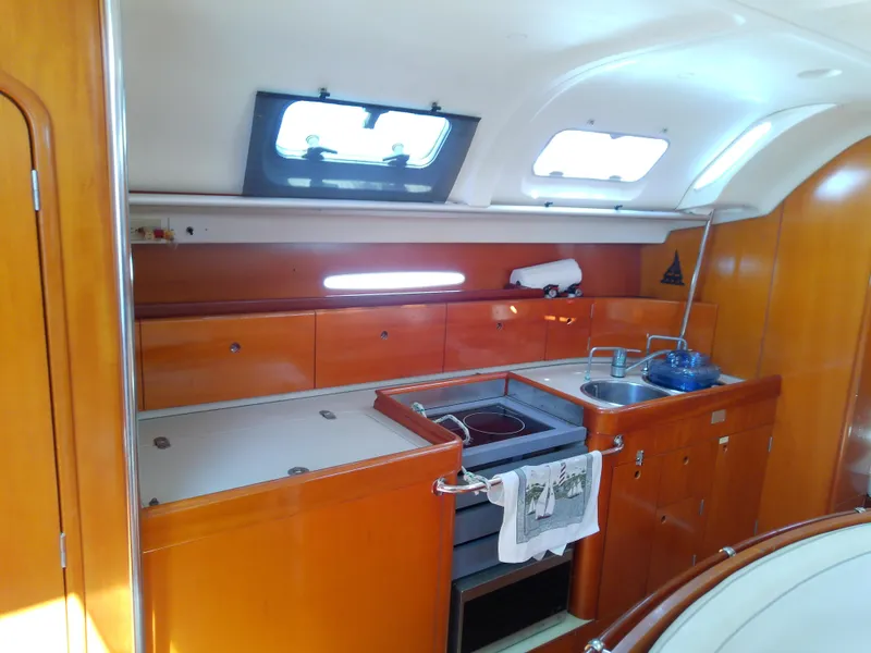Slide: The Image of Interior of 1995 Beneteau First 42s7 yacht, featuring a compact kitchen with wood cabinetry. - 40