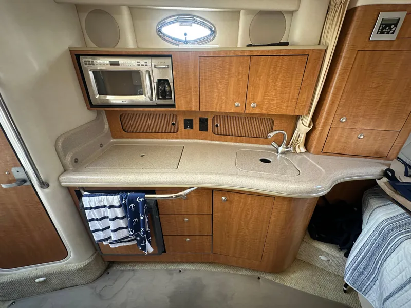 Slide: The Image of 2006 Sea Ray 320 Sundancer kitchen area with microwave, sink, and wooden cabinetry. - 11