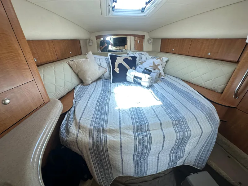 Slide: The Image of Cozy cabin interior of 2006 Sea Ray 320 Sundancer with striped bedding and decorative pillows. - 12