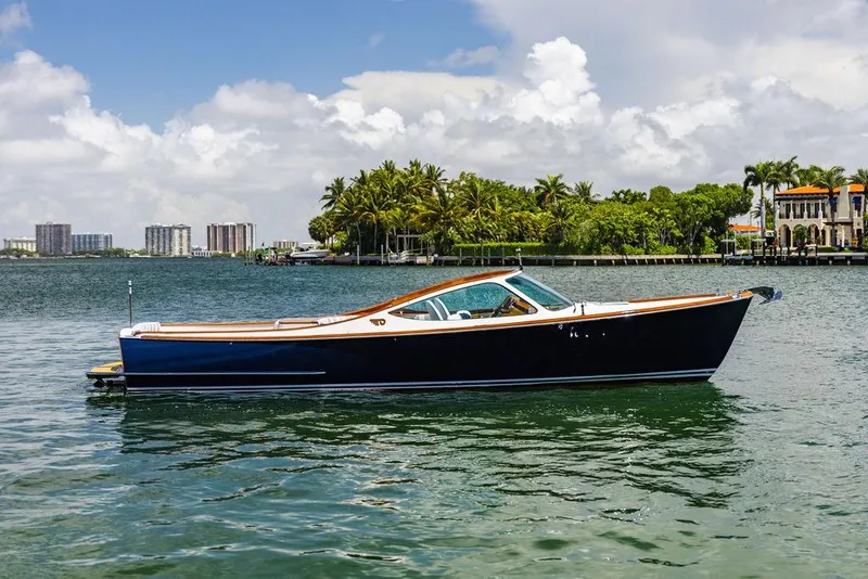 Slide: The Image of 2004 Hinckley Talaria 29 R boat on calm water with palm trees in the background. - 1