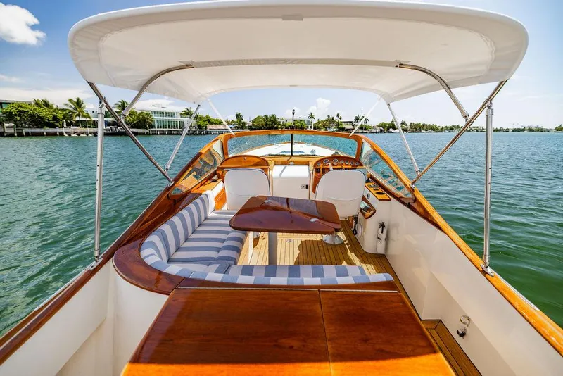 Slide: The Image of 2004 Hinckley Talaria 29 R boat with elegant wood finish and striped seating on calm water. - 16