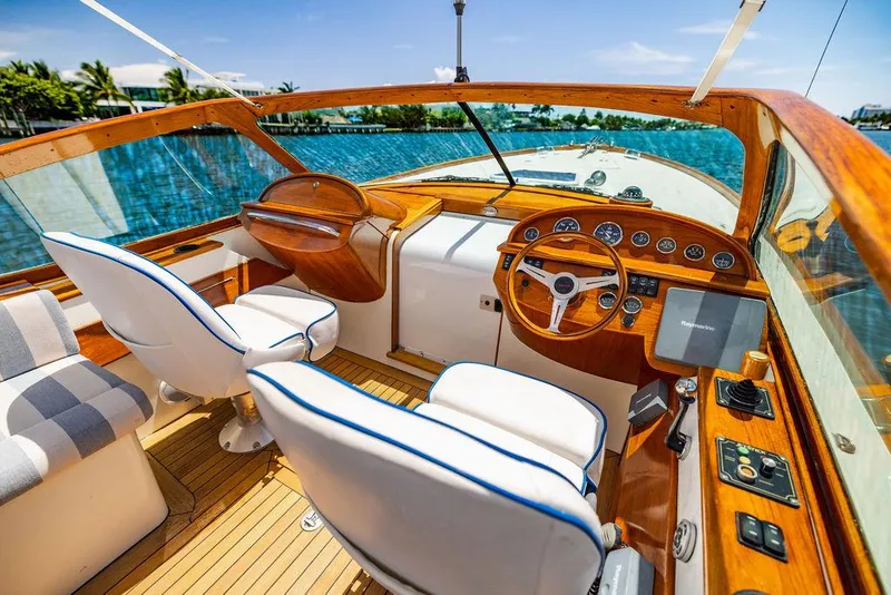 Slide: The Image of 2004 Hinckley Talaria 29 R boat interior with wooden dashboard and white seating. - 19