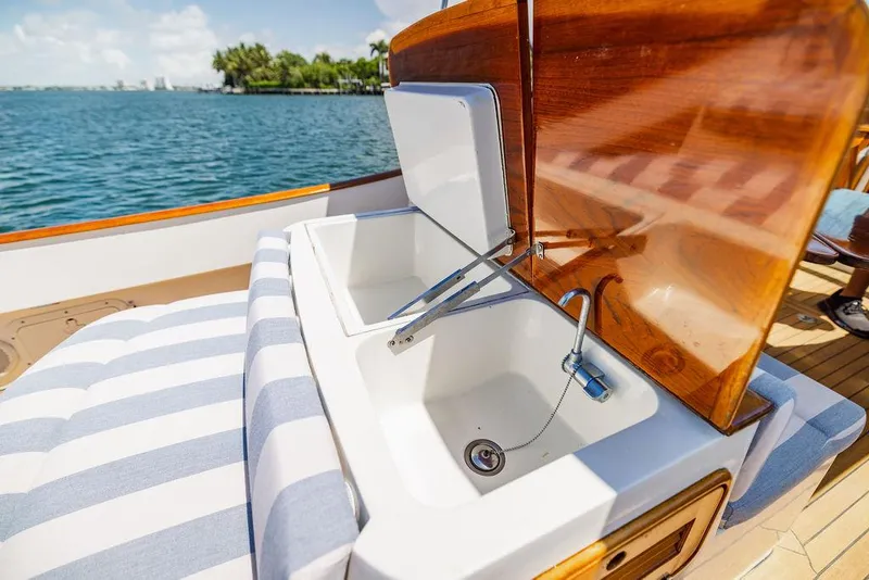Slide: The Image of 2004 Hinckley Talaria 29 R yacht with open storage compartment, striped seating, and ocean view. - 24