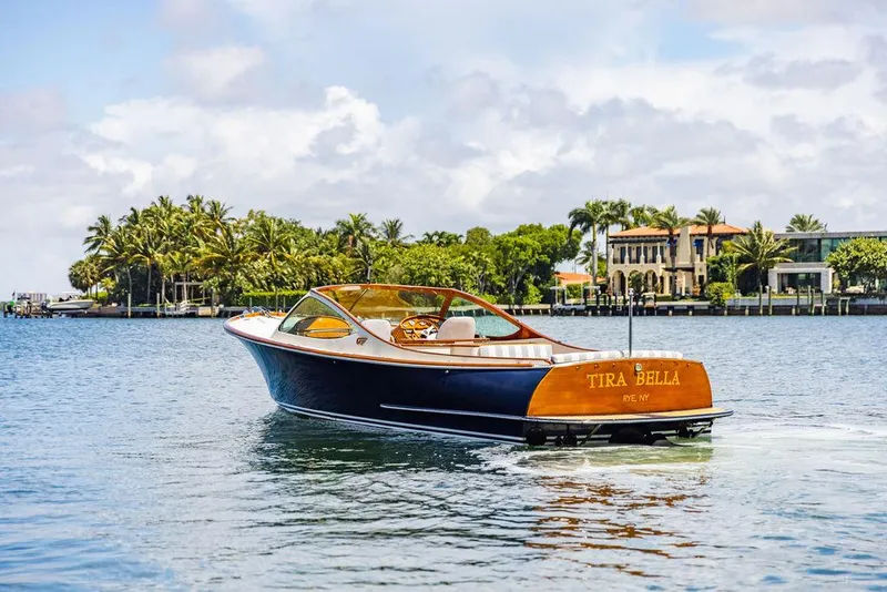 Slide: The Image of 2004 Hinckley Talaria 29 R boat cruising on a scenic waterfront with palm trees. - 28