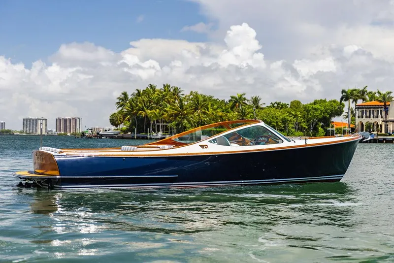 Slide: The Image of 2004 Hinckley Talaria 29 R boat on calm water with palm trees in the background. - 29