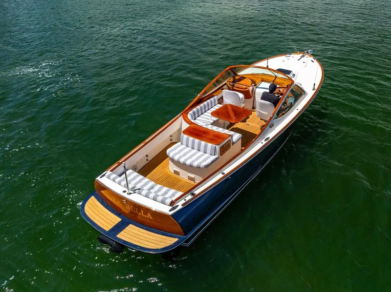 Slide: The Image of 2004 Hinckley Talaria 29 R boat on water, featuring elegant design and striped seating. - 33